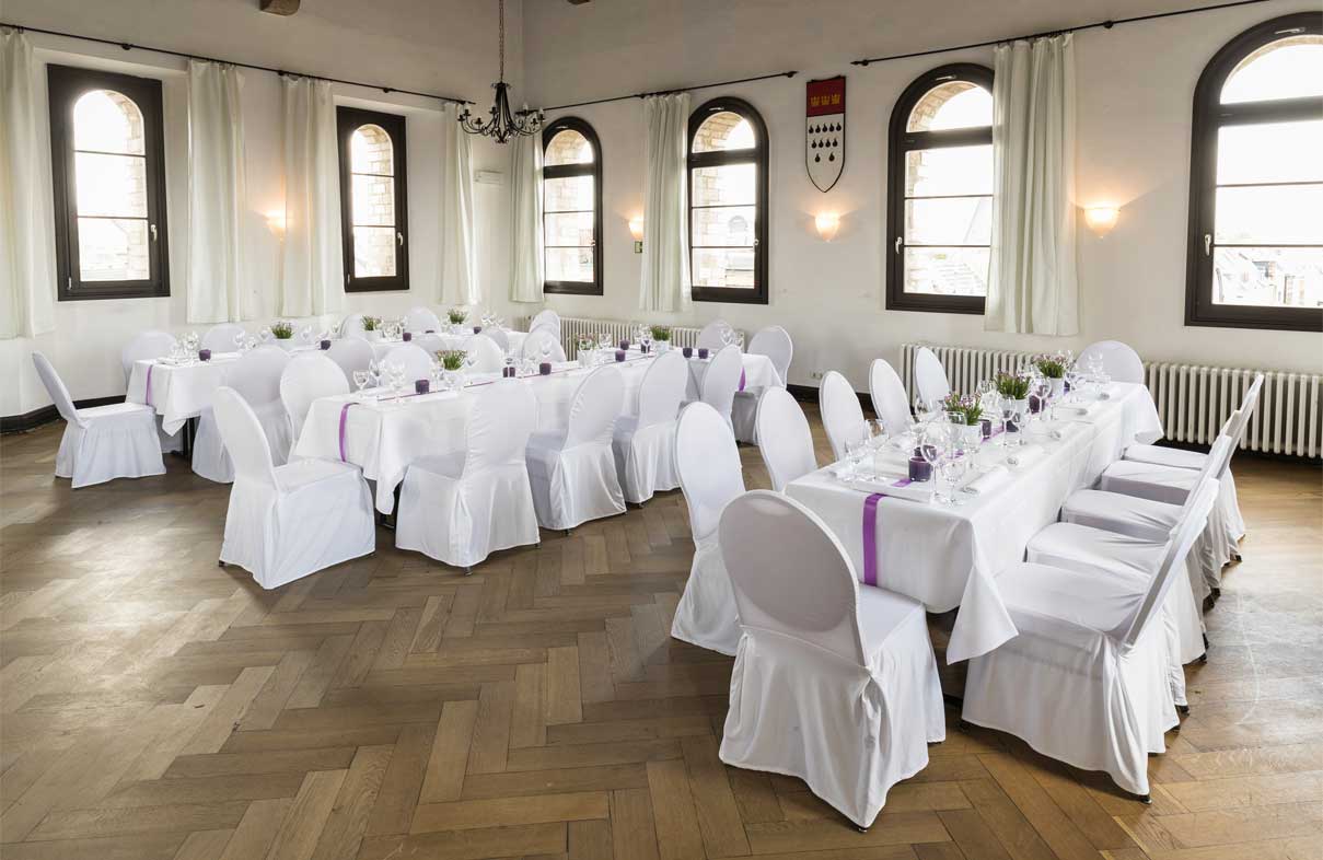 Festsaal- Blick in den Raum mit gedeckten Tischen, Parkettboden und Rundbogenfenstern